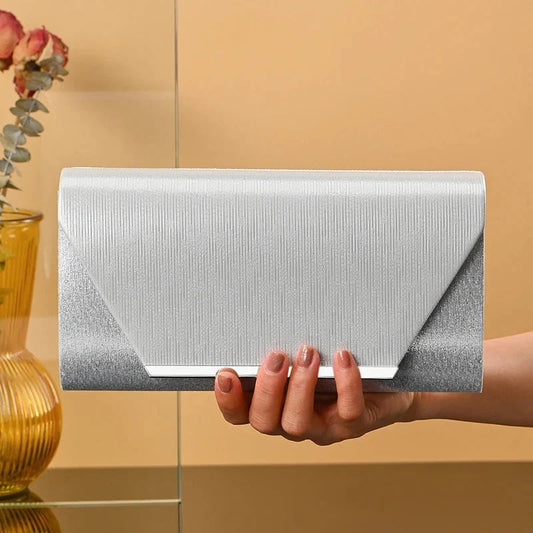 Silver chic wedding crossbody bag held in hand with textured surface and geometric flap