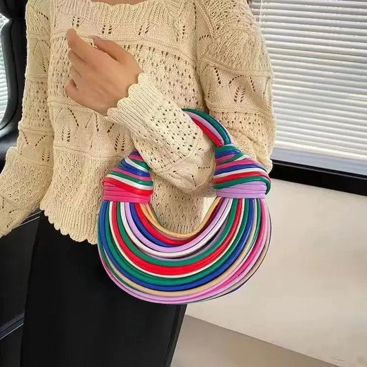 Colorful multistripe round handbag with thick rope handles held by person in beige knit sweater