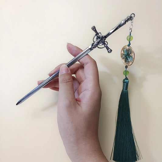 LIVSY sword tassel hairpin with silver sword design and green tassel held in hand
