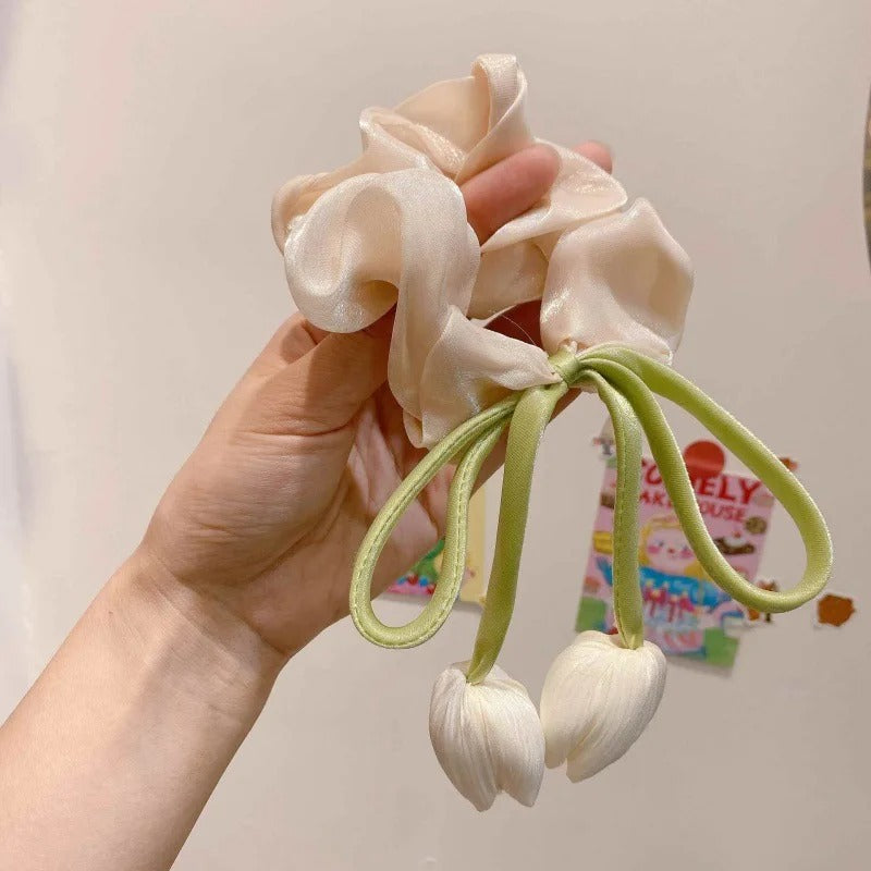 Hand holding LIVSY Korean style satin scrunchies in cream with green tulip decoration
