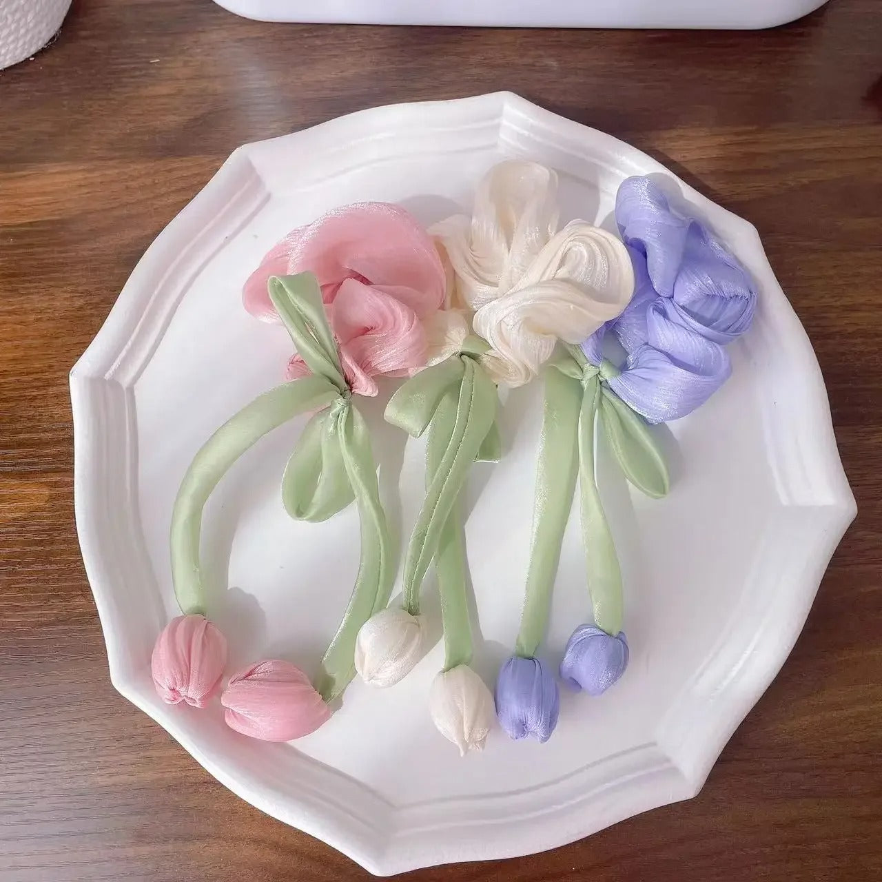 LIVSY Korean style satin scrunchies in pink white and purple with green ribbon stems on white plate