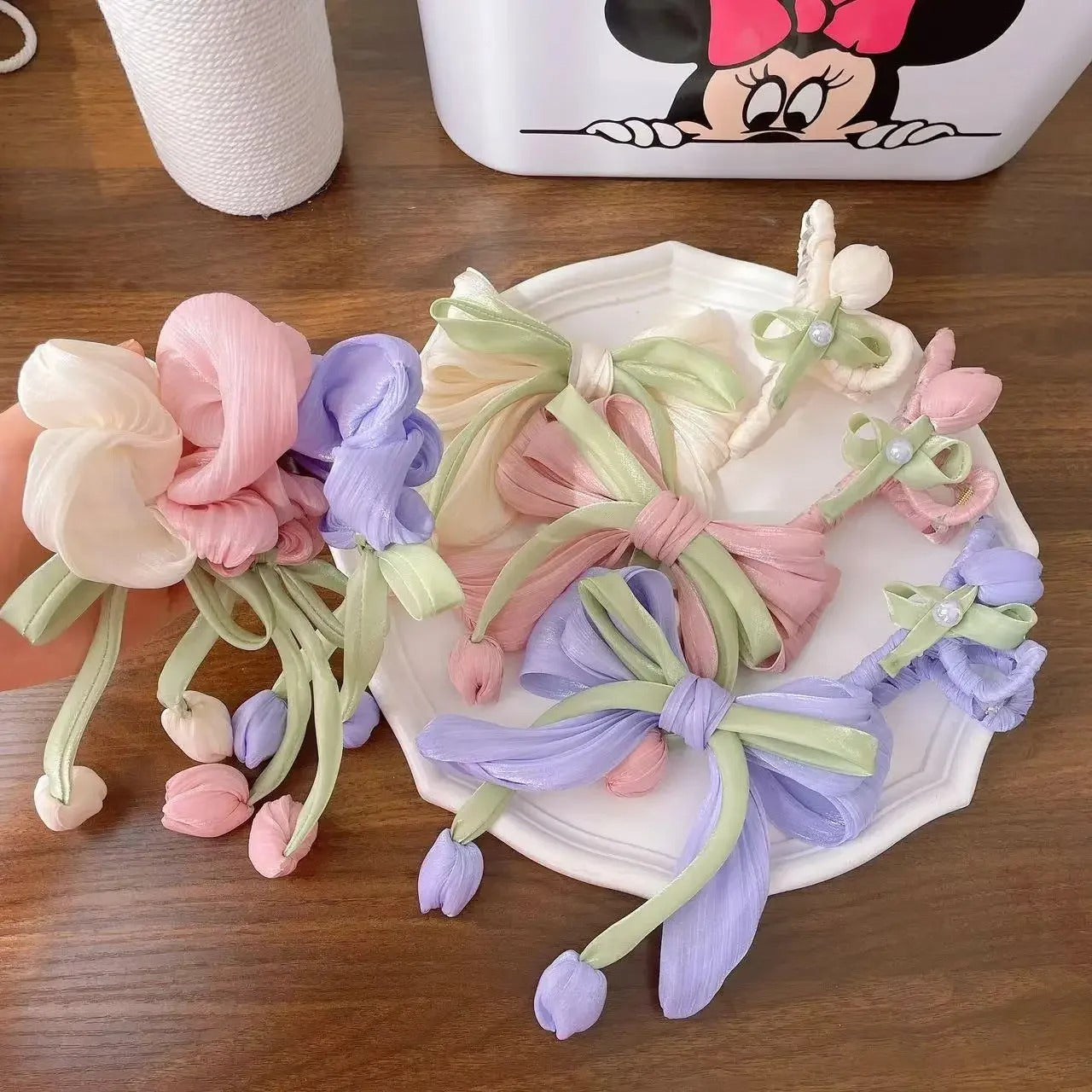 LIVSY Korean style satin scrunchies in pastel pink purple and cream with green ribbons on white plate